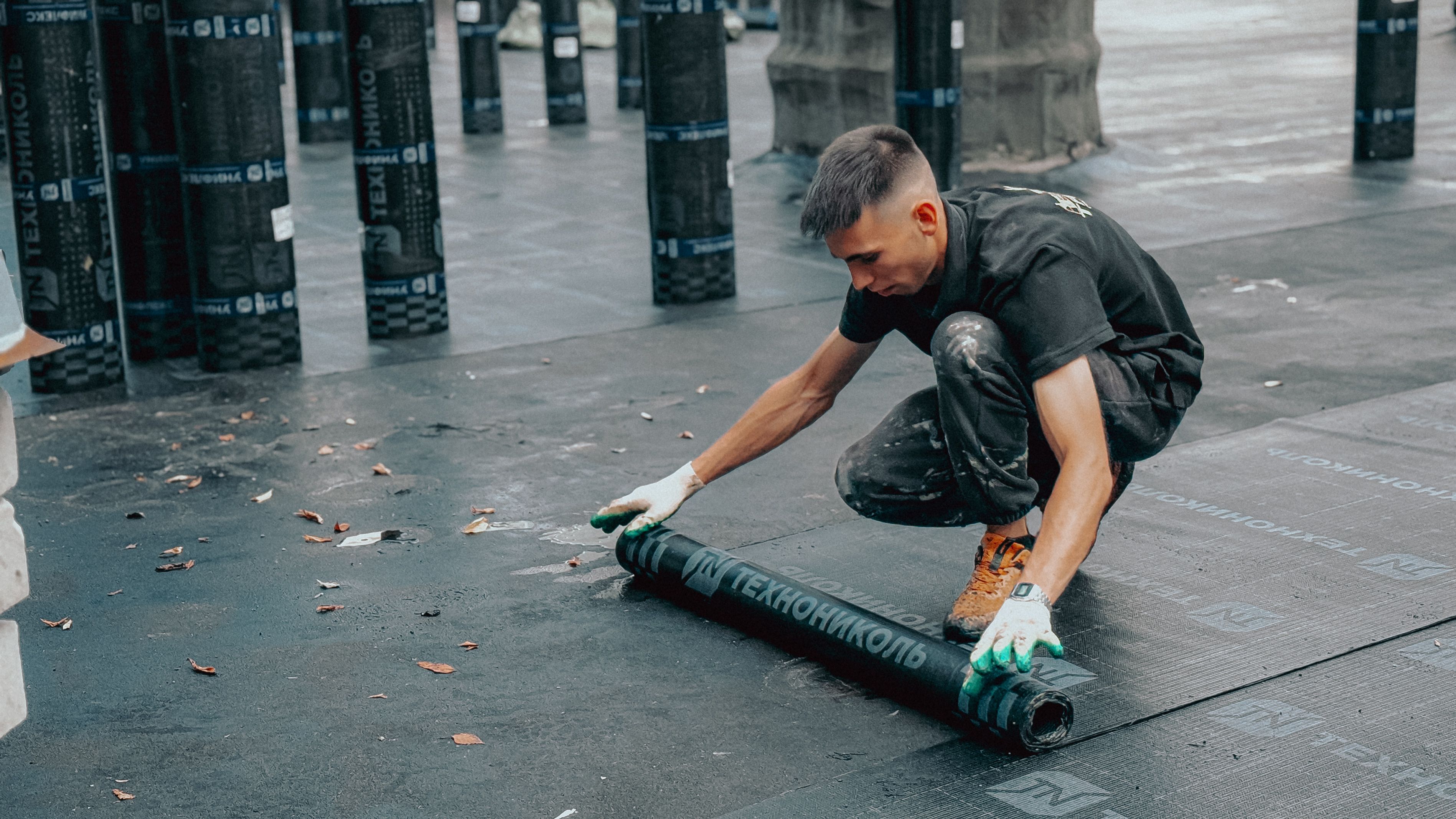 Construction worker applying a waterproof membrane to protect a building from water damage.