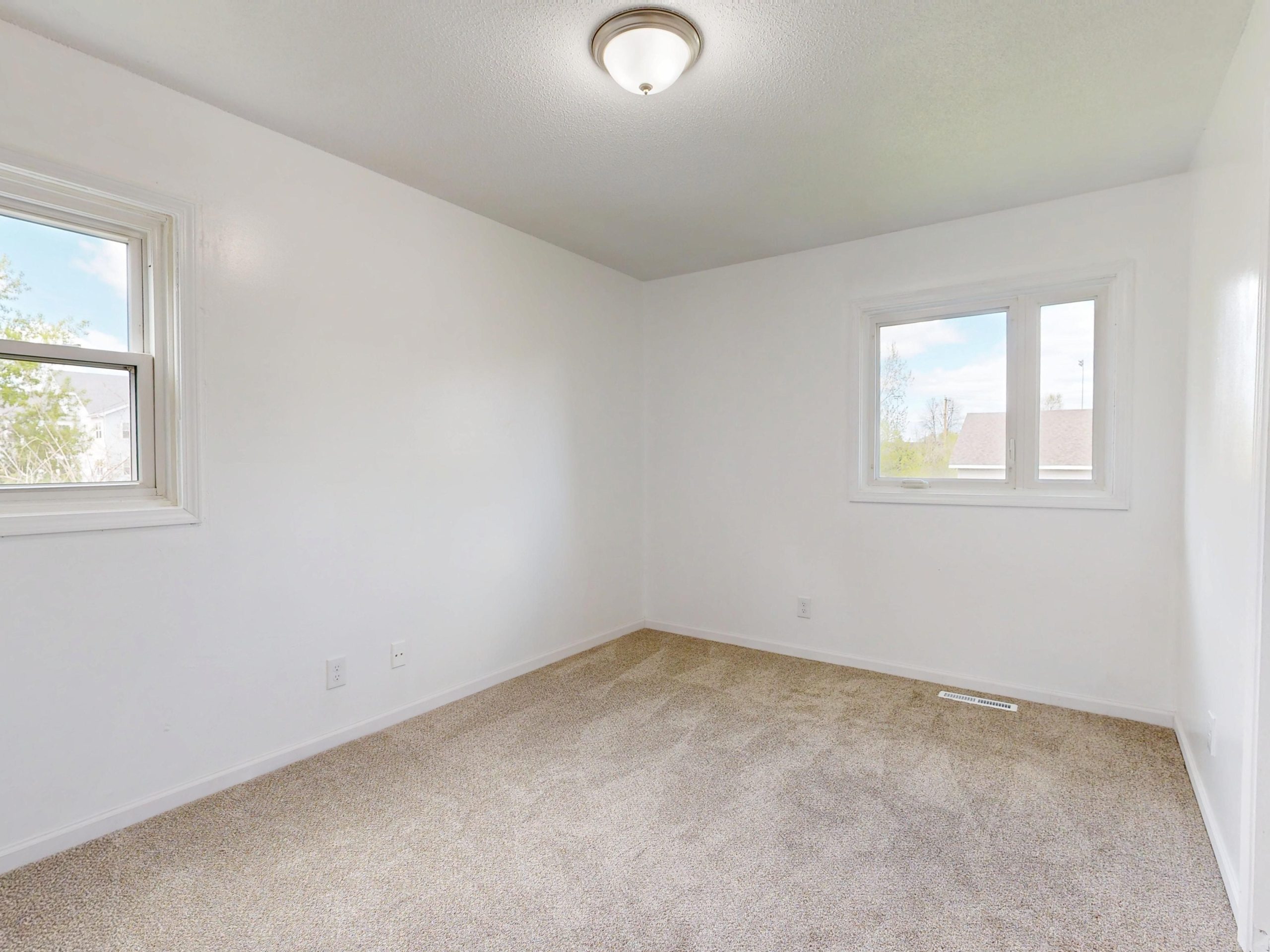 Spacious empty room with white walls and neutral flooring in a new home before move-in renovations.