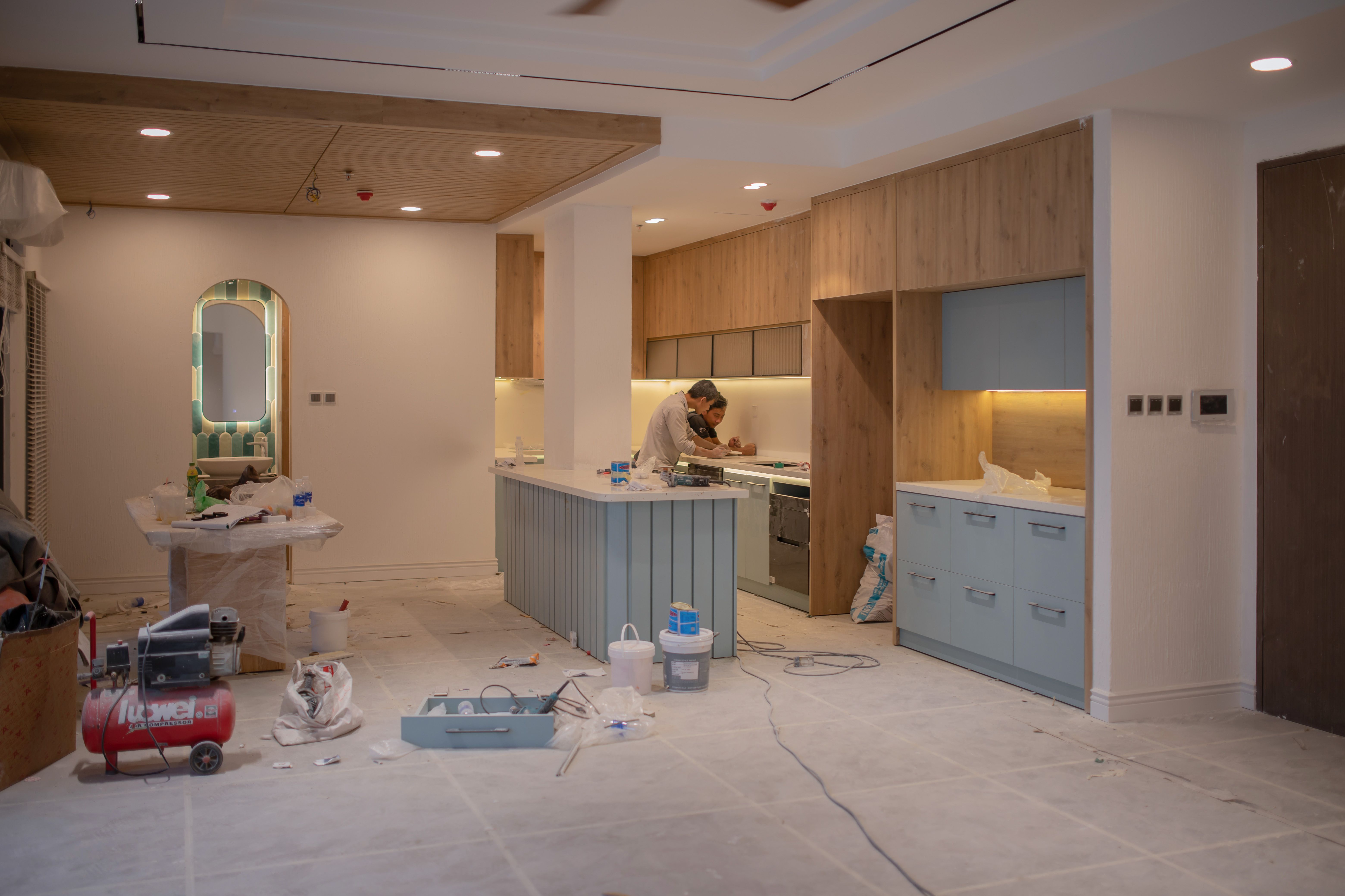 Worker renovating a modern kitchen with tools and construction materials.
