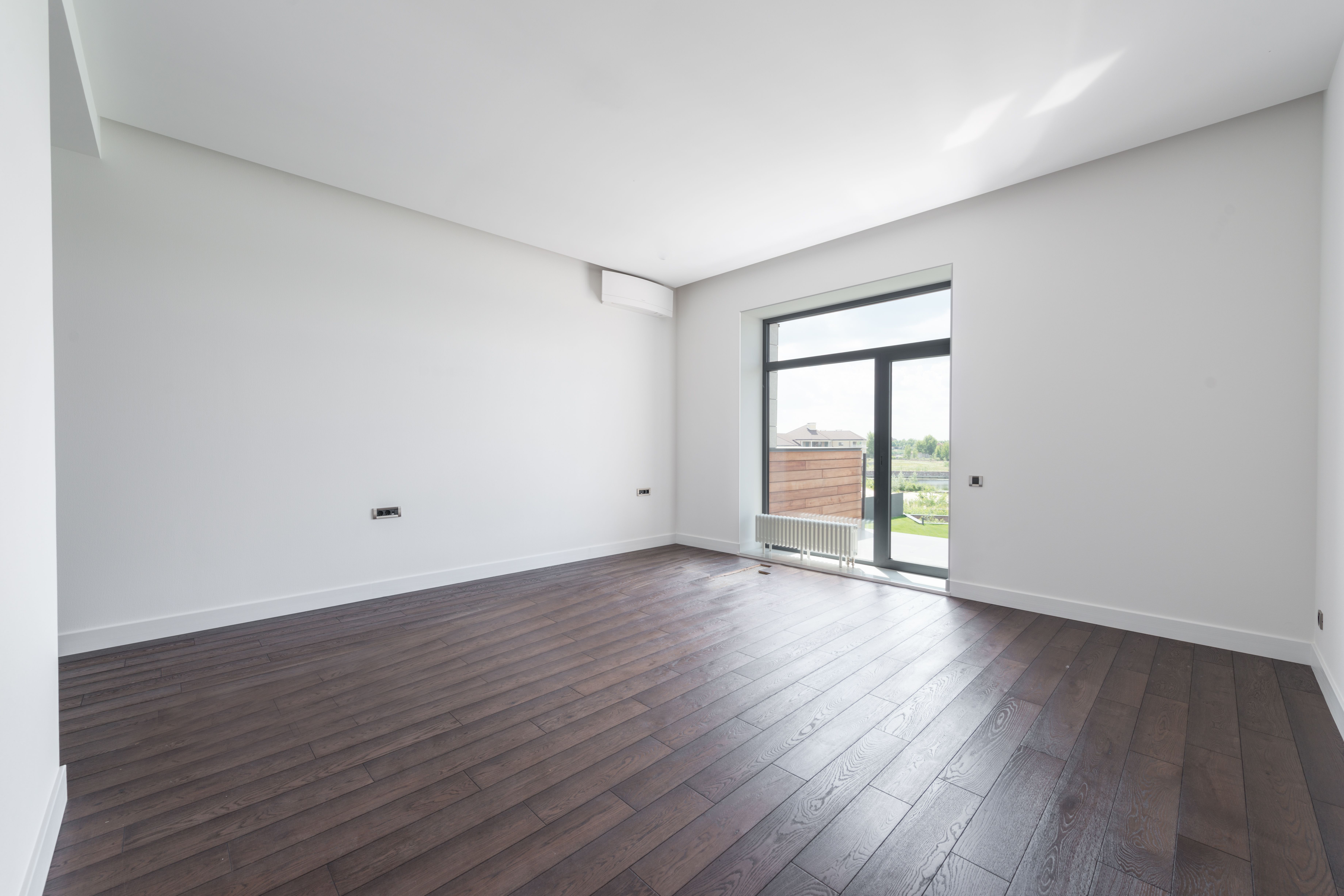 Empty new apartment room with wooden parquet flooring and white walls ready for move-in.