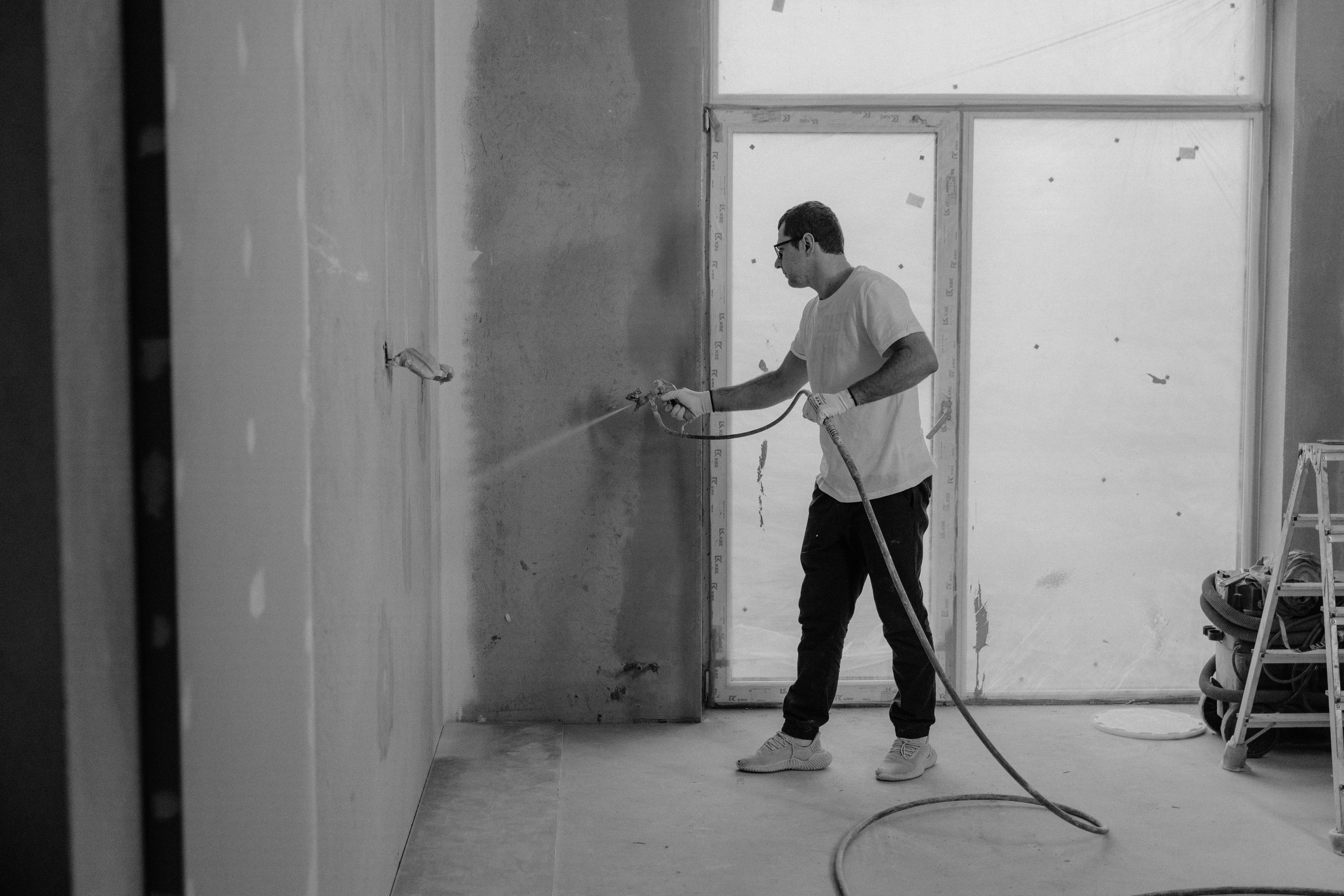 Worker painting an interior wall during a home renovation.