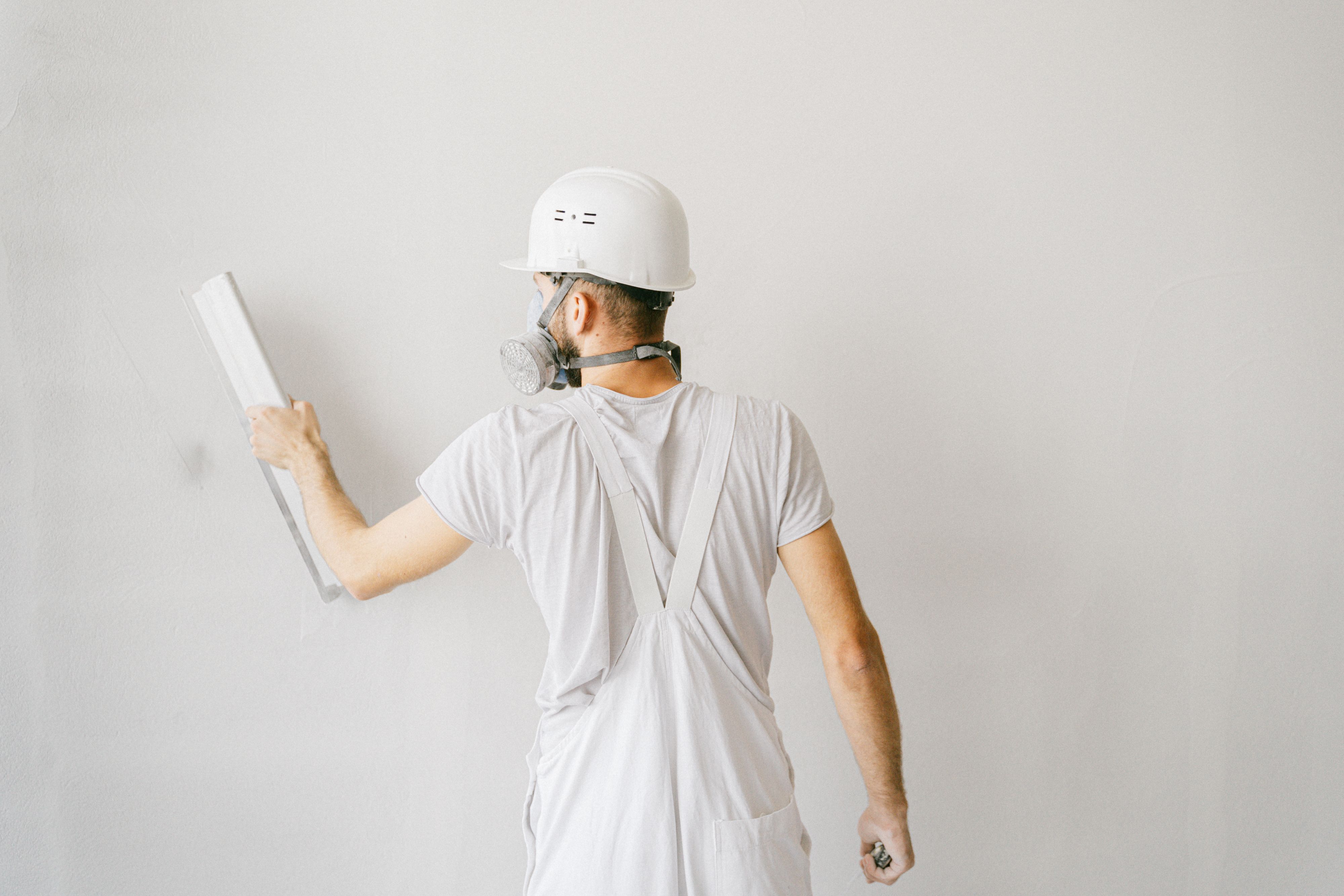 Construction worker plastering a wall, illustrating render repair and maintenance work.